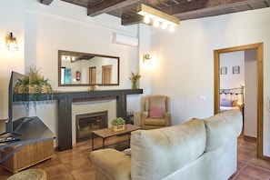 A living room with a fireplace, a sofa, a chair, a television, and a mirror.