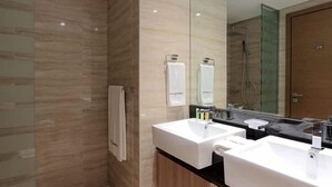 Une salle de bain moderne avec deux lavabos, une douche à l’italienne en verre et un grand miroir.