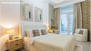 Une chambre à coucher moderne avec un grand lit, des tables de chevet, un fauteuil et des œuvres d’art accrochées aux murs.