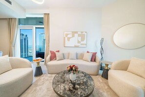 Un salon moderne comprenant un canapé, deux fauteuils, une table basse et une vue sur la ville grâce à de grandes fenêtres.