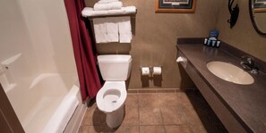 Un baño con inodoro, lavamanos y bañera. Hay toallas y artículos de aseo en el mostrador.