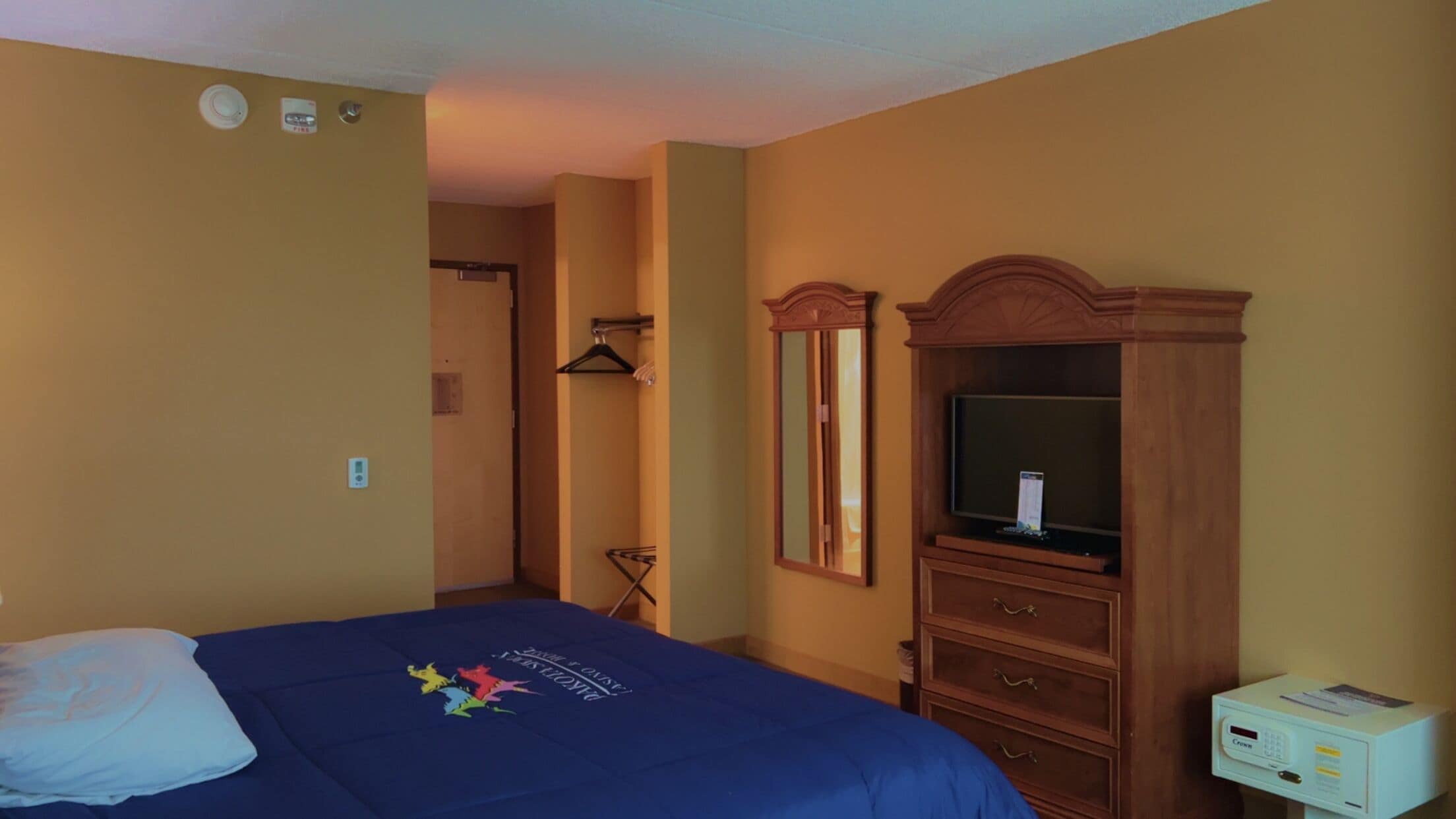 A hotel room with a bed, a dresser, a television, and a small desk with a computer.