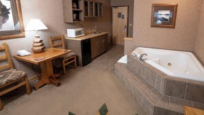 Un baño compacto con bañera, lavamanos y una pequeña mesa con una silla.