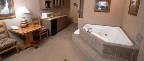 A compact bathroom with a bathtub, a sink, and a small table with a chair.