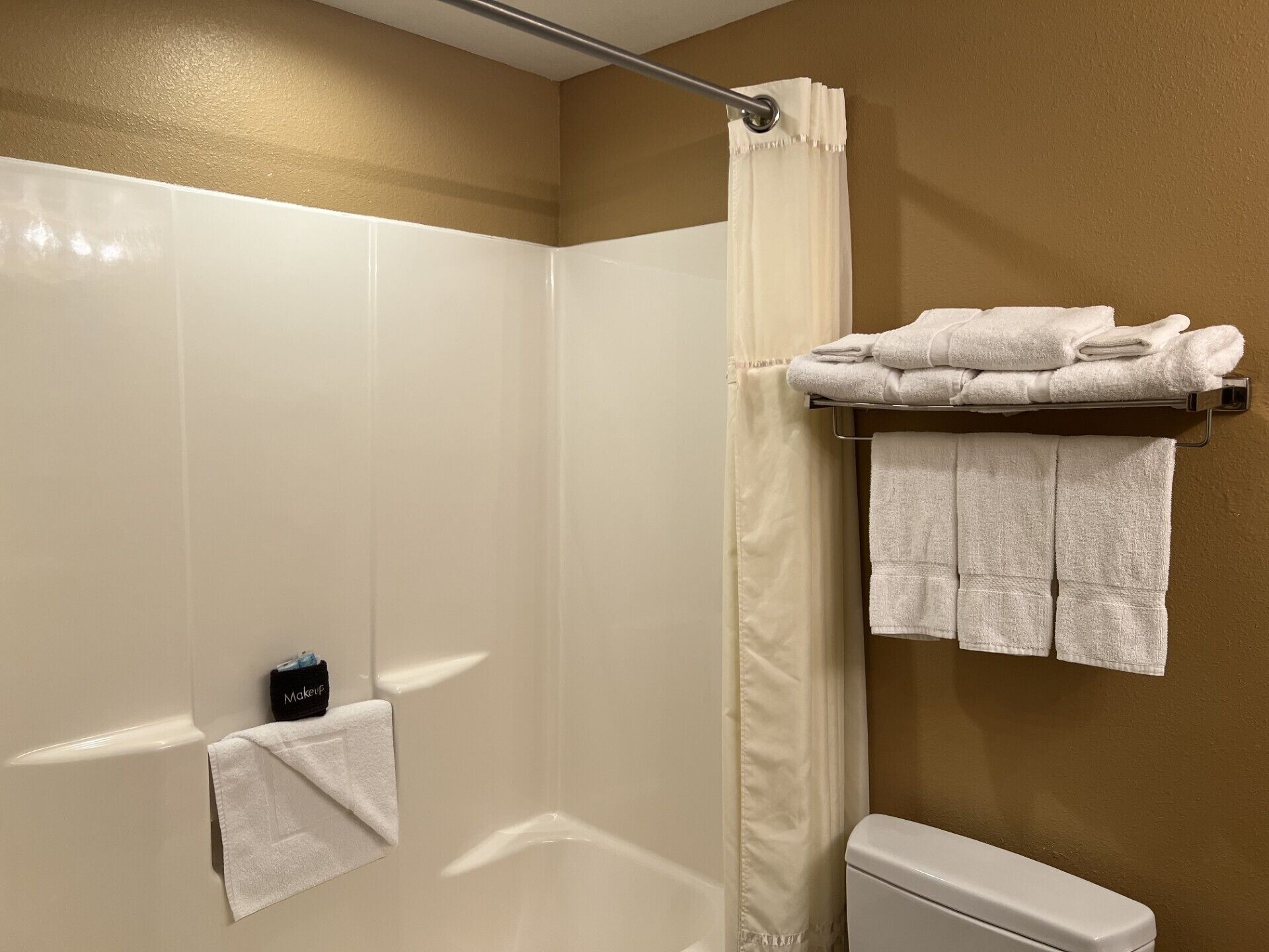 Un baño con ducha, inodoro y perchero para toallas.