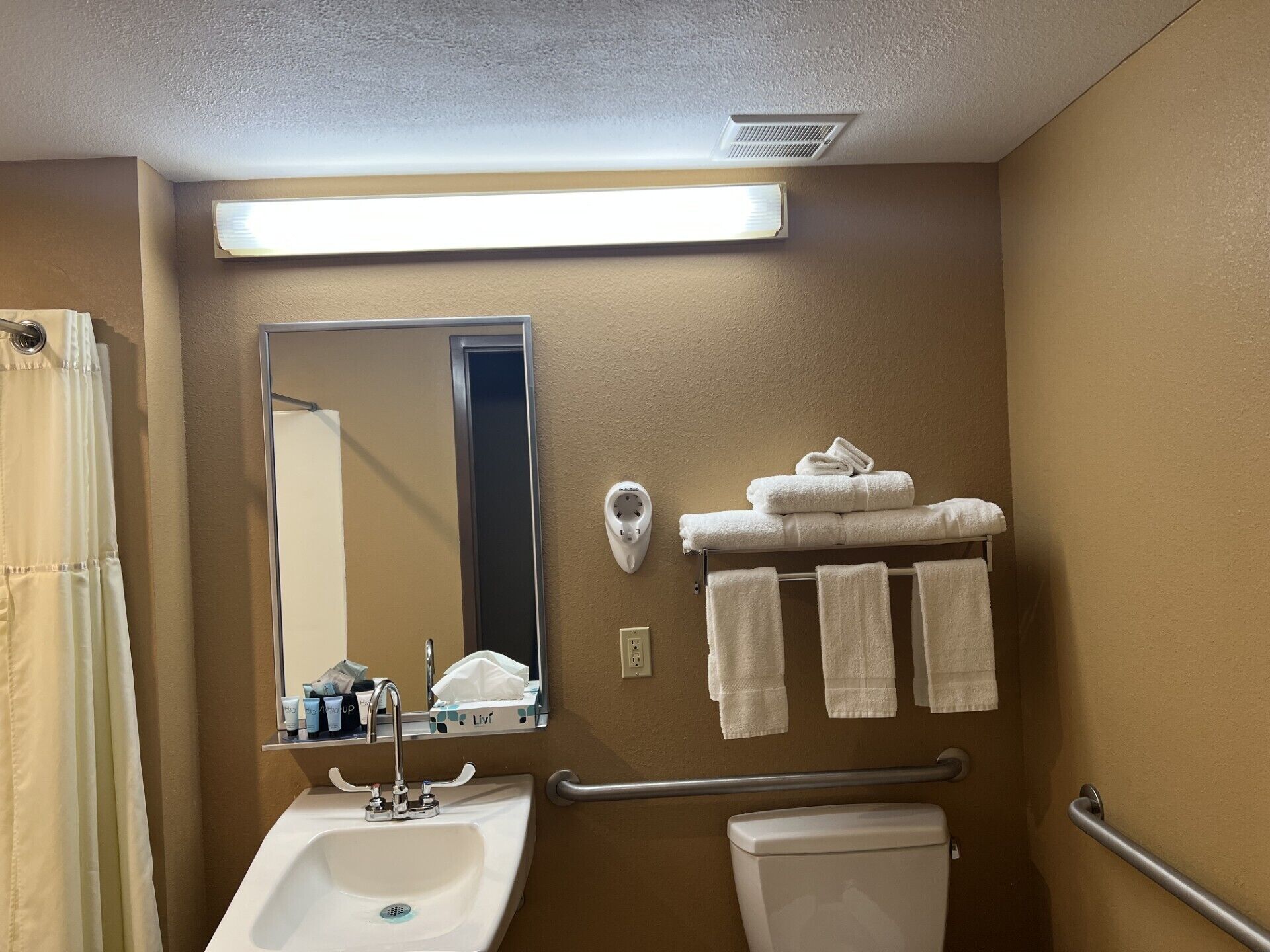 A bathroom with a sink, mirror, towel rack, and toilet.