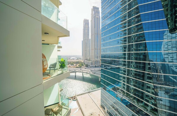 A high-rise building with a glass facade overlooking a river and a bridge.