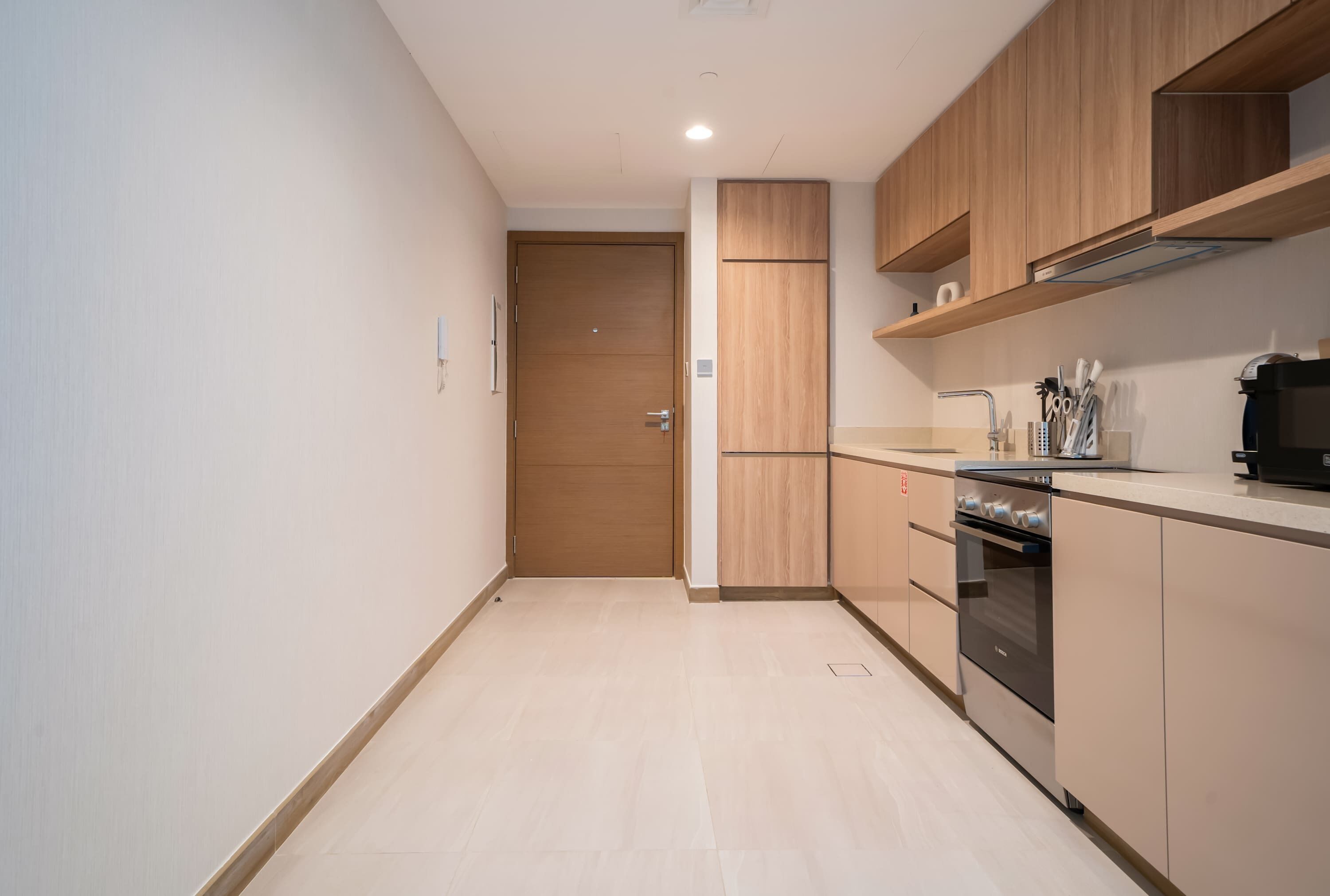 Une cuisine moderne avec des meubles en bois, un four encastré et un plan de travail équipé d’ustensiles de cuisine.