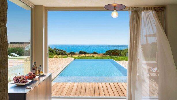 Un balcó amb piscina, una terrassa de fusta i vista al mar.