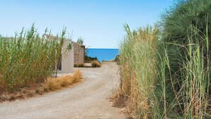 Un camí de terra que condueix a un edifici de pedra amb vista al mar.