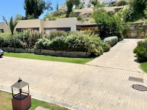 Un camino de entrada residencial con un sendero pavimentado, un muro de piedra y un coche estacionado.