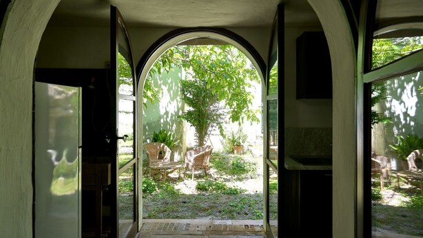 An arched doorway leading to a garden area with outdoor furniture and a tree. - GuestHost - Relax in the natural park/20 minutes from the sea (Sassari)