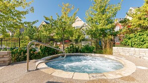 A hot tub surrounded by a stone wall, with a metal railing and a pebble ground. - Blue Sky Retreat at Rivergrass (The Blue Mountains)