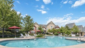 A swimming pool with lounge chairs and umbrellas, surrounded by a fence and trees. - Blue Sky Retreat at Rivergrass (The Blue Mountains)