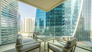 A modern balcony with glass walls, offering a view of high-rise buildings.