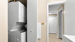 A laundry room with a washer and dryer, a towel rack, and a door leading to another room. - NEW Corp/Bus Townhome New Hudson (New Hudson)