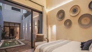 Une chambre moderne avec un grand lit, un petit coin salon, un jacuzzi et une vue sur l’extérieur.