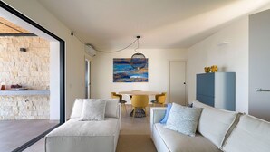 En moderne stue med en sofa, et spisebord med stole og et billede på væggen.