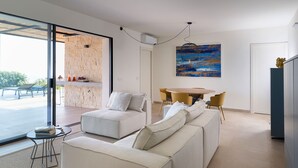 En moderne stue med en sofasæt, et spisebord med stole og et maleri på væggen.