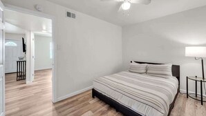 Une chambre à coucher avec un lit, un ventilateur de plafond et une table de chevet.