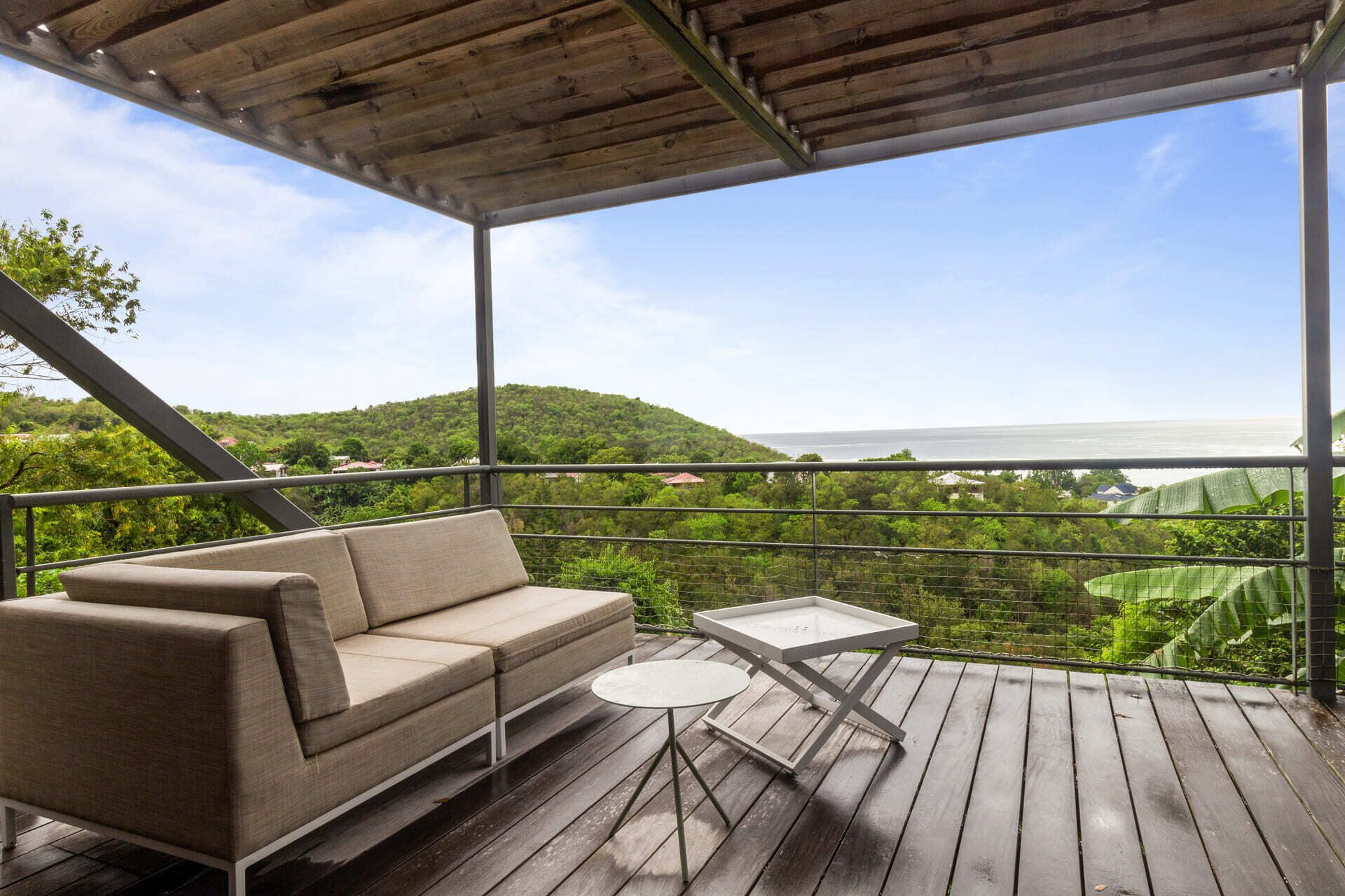 A balcony with a wooden deck, a beige sofa, and a small table.