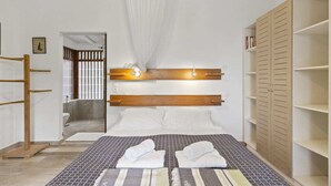 Ein Schlafzimmer mit einem großen Bett, einem Holz-Kopfteil und einem Kleiderschrank mit mehreren Einlegeböden.