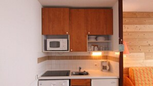 A compact kitchen with wooden cabinets, a microwave, a coffee maker, and a dishwasher. - 100m from ski slopes, 6th floor, balcony, tv, ski locker, 24m², Alpe d'Huez (L'Alpe d'Huez)