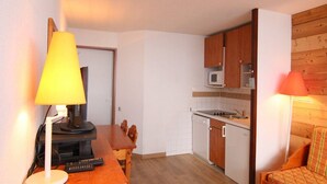 A compact kitchen with wooden cabinets, a microwave, and a dining area with a table and chairs. - 100m from ski slopes, 6th floor, balcony, tv, ski locker, 24m², Alpe d'Huez (L'Alpe d'Huez)