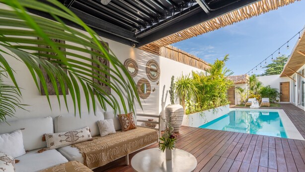 Eine Holzterrasse mit Pool, einer Sitzecke und einem runden Tisch mit Blumen.