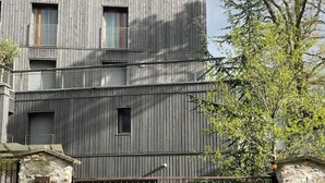 A multi-story building with a metal gate and a stone wall.