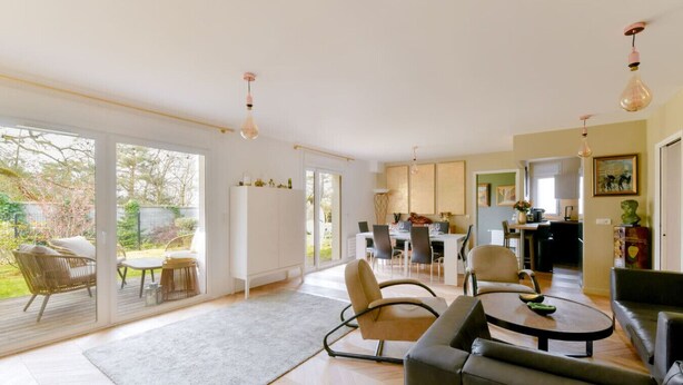 A spacious living area with a dining table, sofas, and a kitchen in the background.
