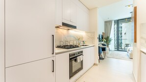 A modern kitchen with white cabinets, a built-in oven, and a gas stove.