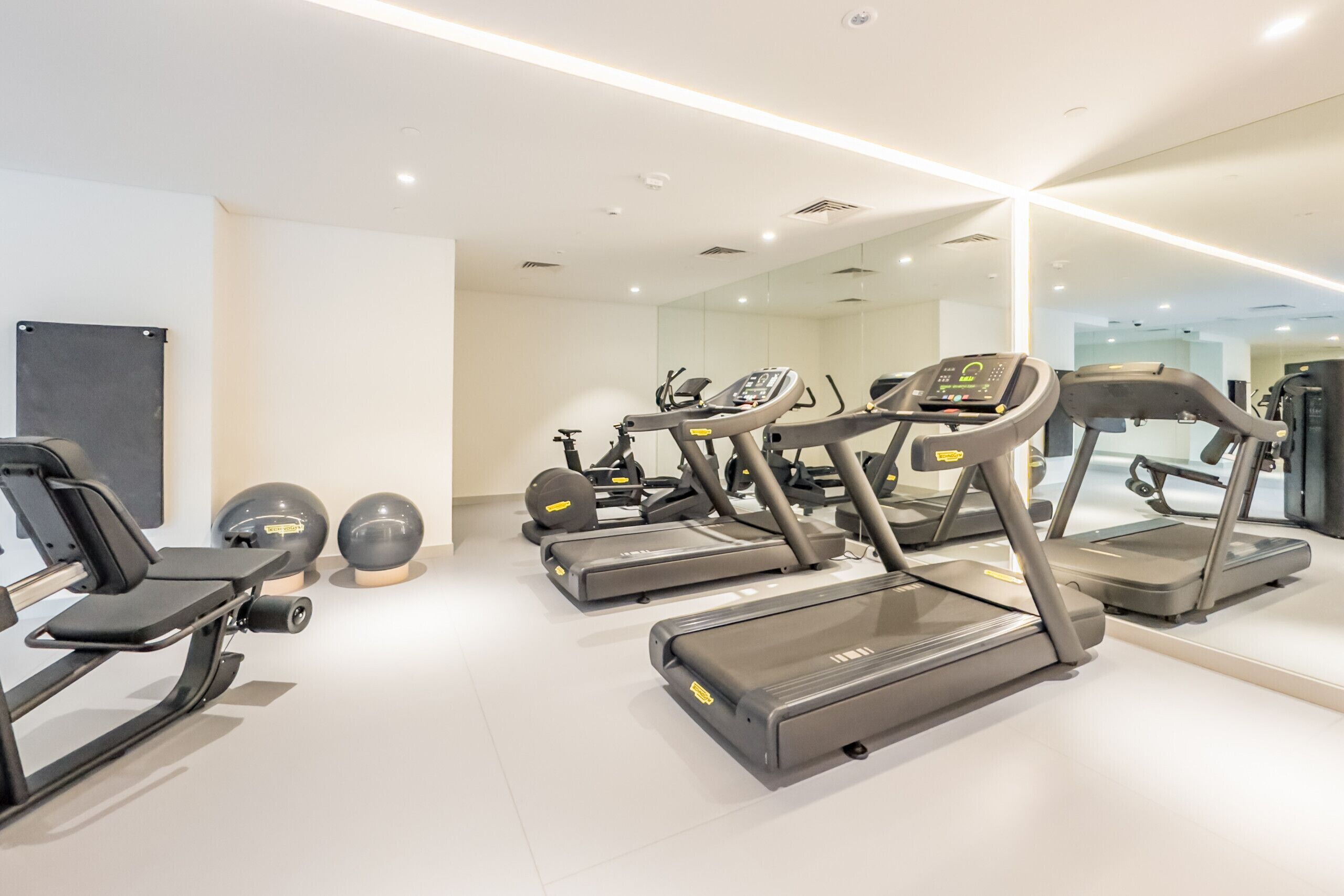 A modern gym with treadmills, weight machines, and exercise balls.