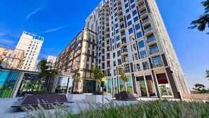 Un immeuble moderne de grande hauteur, doté de nombreux balcons, de grandes fenêtres et d’un jardin sur le toit.
