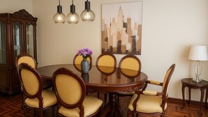 Une salle à manger avec une table ronde, six chaises, un vase de fleurs, un tableau et une lampe.