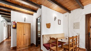 Una habitació amb taula i cadires de fusta, una banca i un armari, a més d'un extintor.