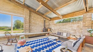 A rustic interior with a stone wall, a fireplace, a sofa, and a large window overlooking a natural landscape. - South Barns a spacious barn conversion near Cowes. (Cowes)