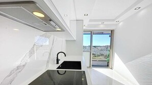Eine moderne Küche mit schwarzem Arbeitsplatz, einem Spülbecken und Blick auf eine Stadt durch eine Glastür.