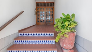 Una escalera con baldosas decoradas que conduce a una puerta de madera con paneles de vidrio.