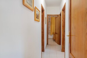 Un couloir avec des portes en bois, un sol carrelé et des tableaux encadrés accrochés au mur.