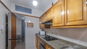 Una cocina con armarios de madera, un refrigerador de acero inoxidable, un microondas, una estufa a gas y un salpicadero de azulejos.
