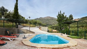 A swimming pool with lounge chairs, a stone patio, and a mountainous backdrop. - Cottage 'Majolero 2' with Shared Pool, Wi-Fi and Air Conditioning (Castillo de Locubín)