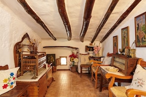 Una habitación tradicional con vigas de madera a la vista, una mesa de madera con sillas, un espejo y una radio antigua.