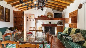 A rustic interior with a dining table, chairs, a sofa, wooden beams, a fireplace, and a wooden ceiling. - Cottage 'Majolero 2' with Shared Pool, Wi-Fi and Air Conditioning (Castillo de Locubín)