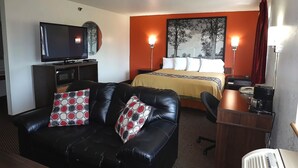 Una habitación de hotel con una cama, un sofá de cuero negro, un televisor y un escritorio con cafetera.