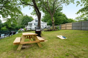 Een achtertuin met een picknicktafel, een barbecue en een zwembad.
