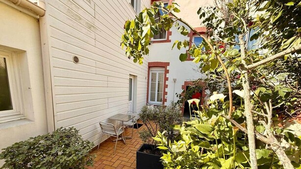 A patio area with a table and chairs, surrounded by potted plants and a small tree. - Studio 1 - Place to B "Alizé (Saint-Nazaire)