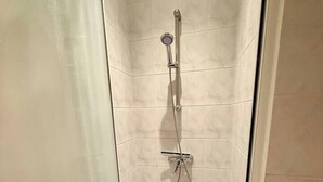 A small, enclosed shower area with a glass door, a handheld showerhead, and a wall-mounted faucet. - Studio 1 - Place to B "Alizé (Saint-Nazaire)