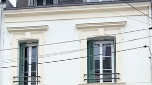 A two-story building with a green door and shutters, a small balcony, and a stone foundation. - Studio 1 - Place to B "Alizé (Saint-Nazaire)