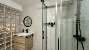 A bathroom with a glass shower enclosure, a wooden vanity with a white sink, and a frosted glass partition. - Cruzeiro by Check-in Portugal (Quarteira)
